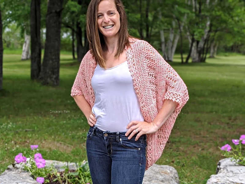 Model is standing in a garden while wearing the Daphne cocoon cardigan crochet pattern by Sincerely Pam