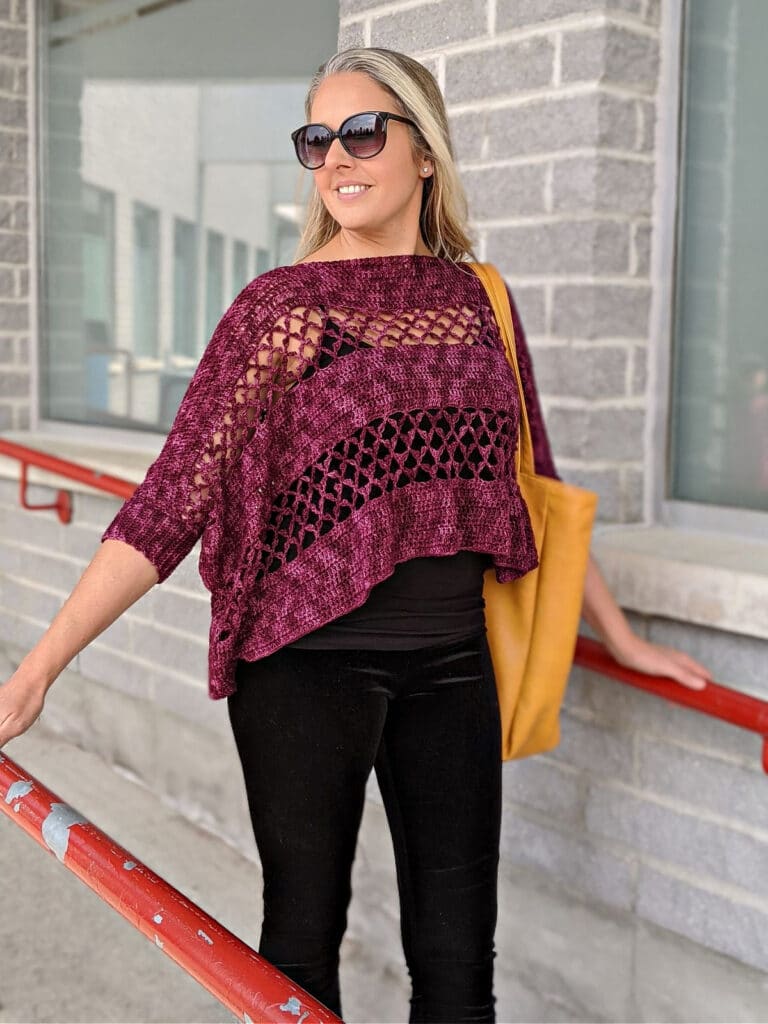 A woman wearing the Contessa Cropped Pullover pattern is walking down a ramp, carrying a WeCrochet tote bag.