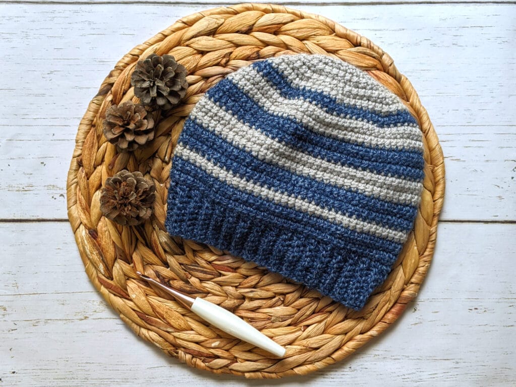 alex beanie laying on a rattan circle with pinecones and a furls odyssey hook.