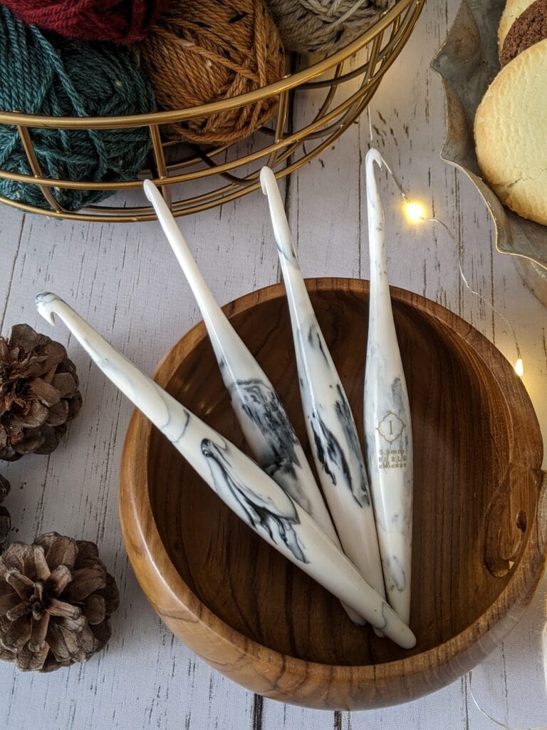 cookie and cream streamline swirl hooks sit in a teak yarn bowl by furls crochet.