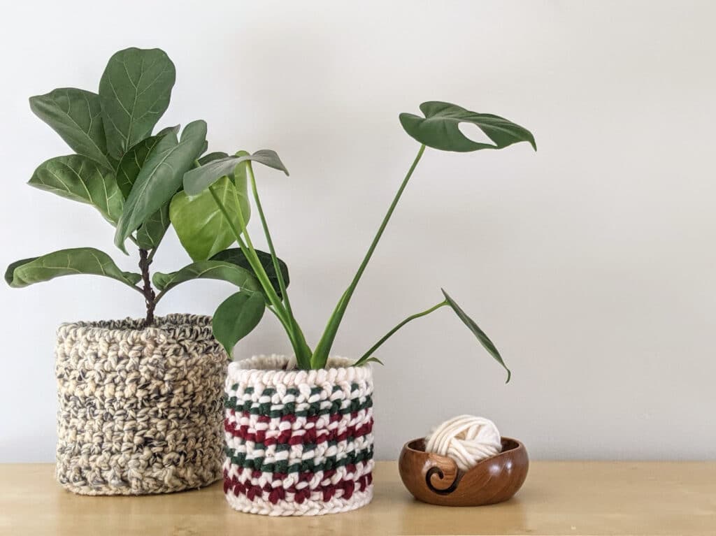 Totally Textured crochet baskets in Lion Brand Wool-ease thick and quick and Tuff Puff yarn sit on a table with plants in them. A teak Furls crochet yarn bowl sits beside them.